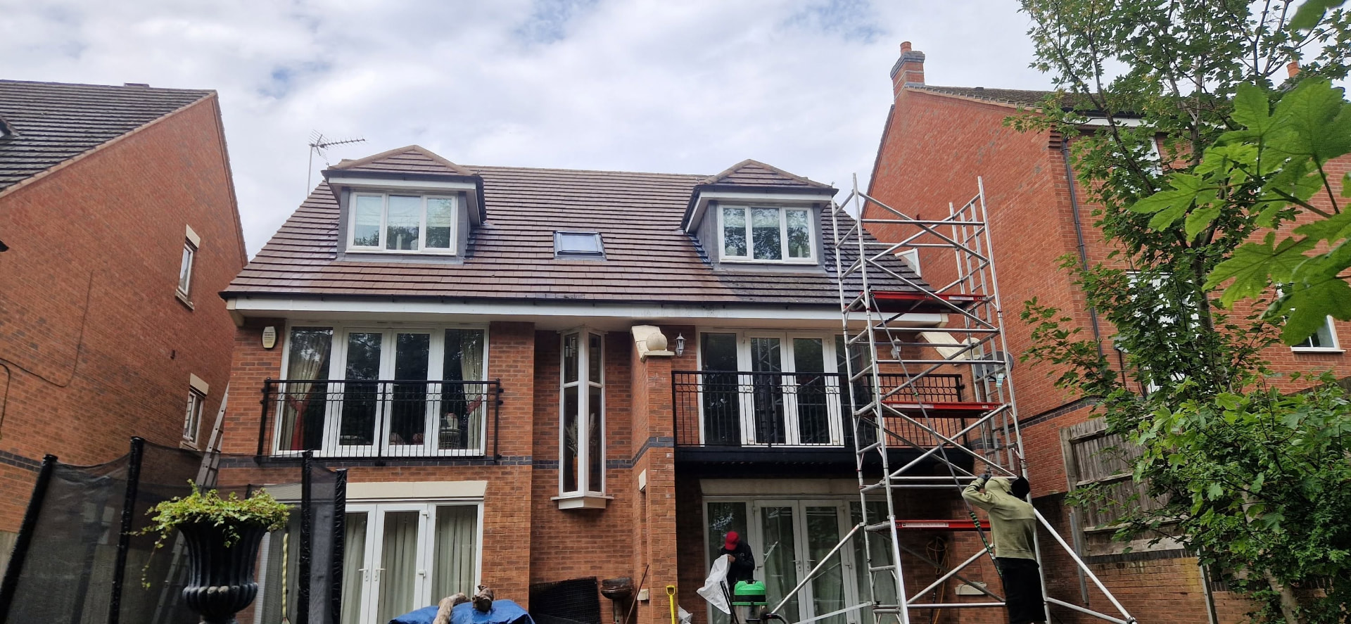 Roof cleaning in progress on a detached house using tower access in Redditch, Worcestershire