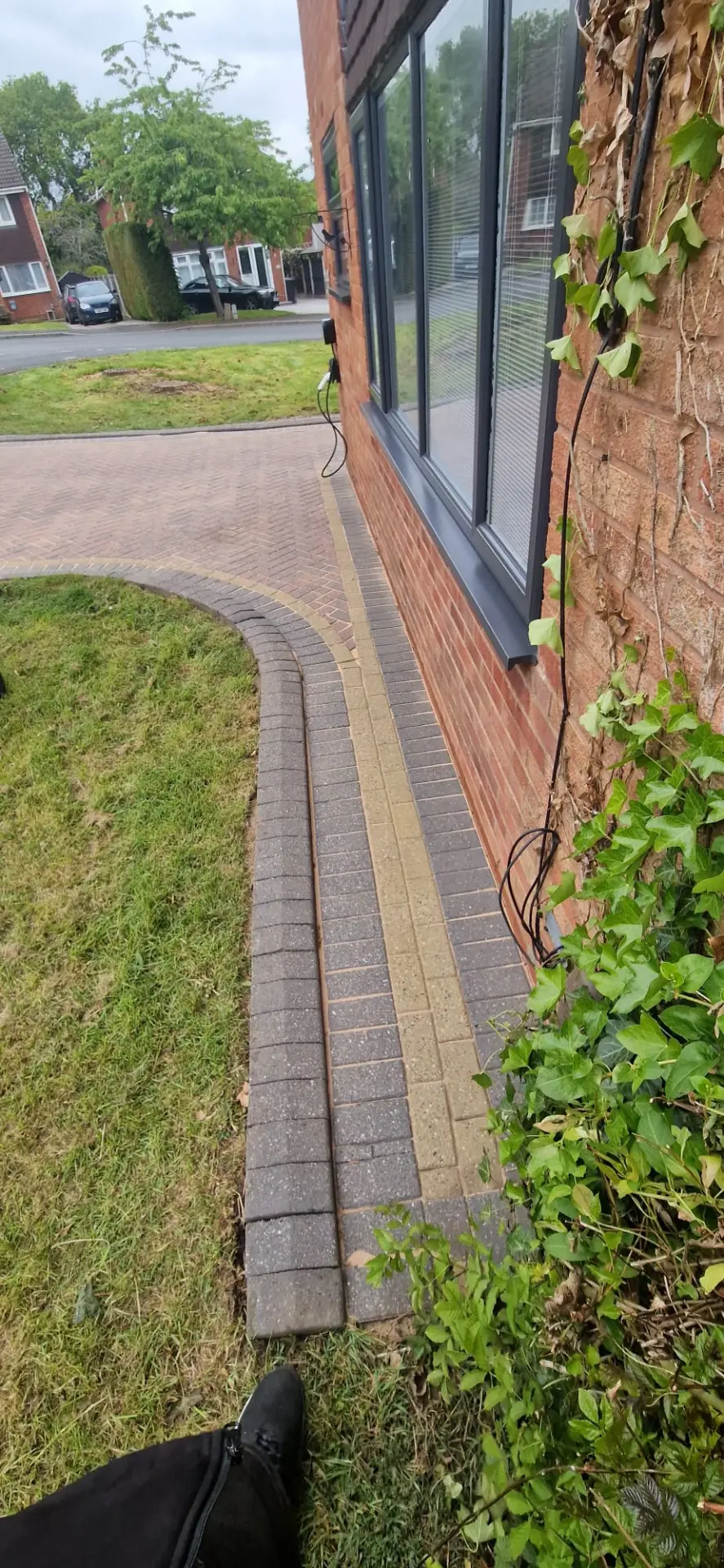 Block paved pathway and driveway edge cleaned alongside a brick house in Redditch, Worcestershire